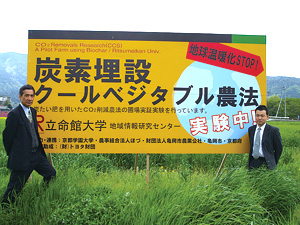 亀岡駅に隣接する小麦畑に設置された看板（右が筆者）
