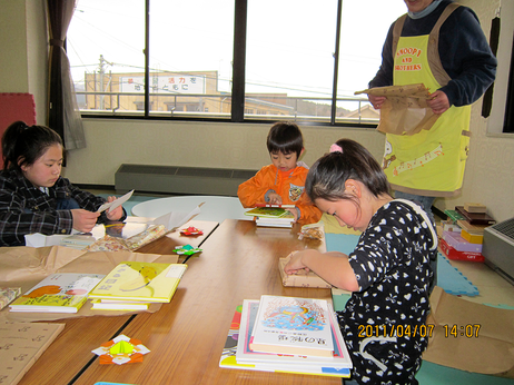 届けられた絵本をさっそく読みはじめる子どもたち（野田村の児童クラブ2011年4月7日）。東日本大震災発生後、ＮＰＯ法人岩手子ども環境研究所（森と風のがっこう）は、子どもを中心とする被災者へのサポートを行った